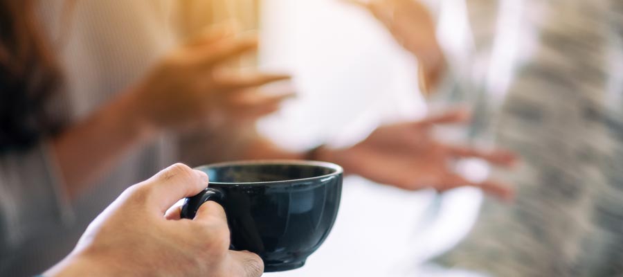 Hände gestikulierend und Kaffeetasse